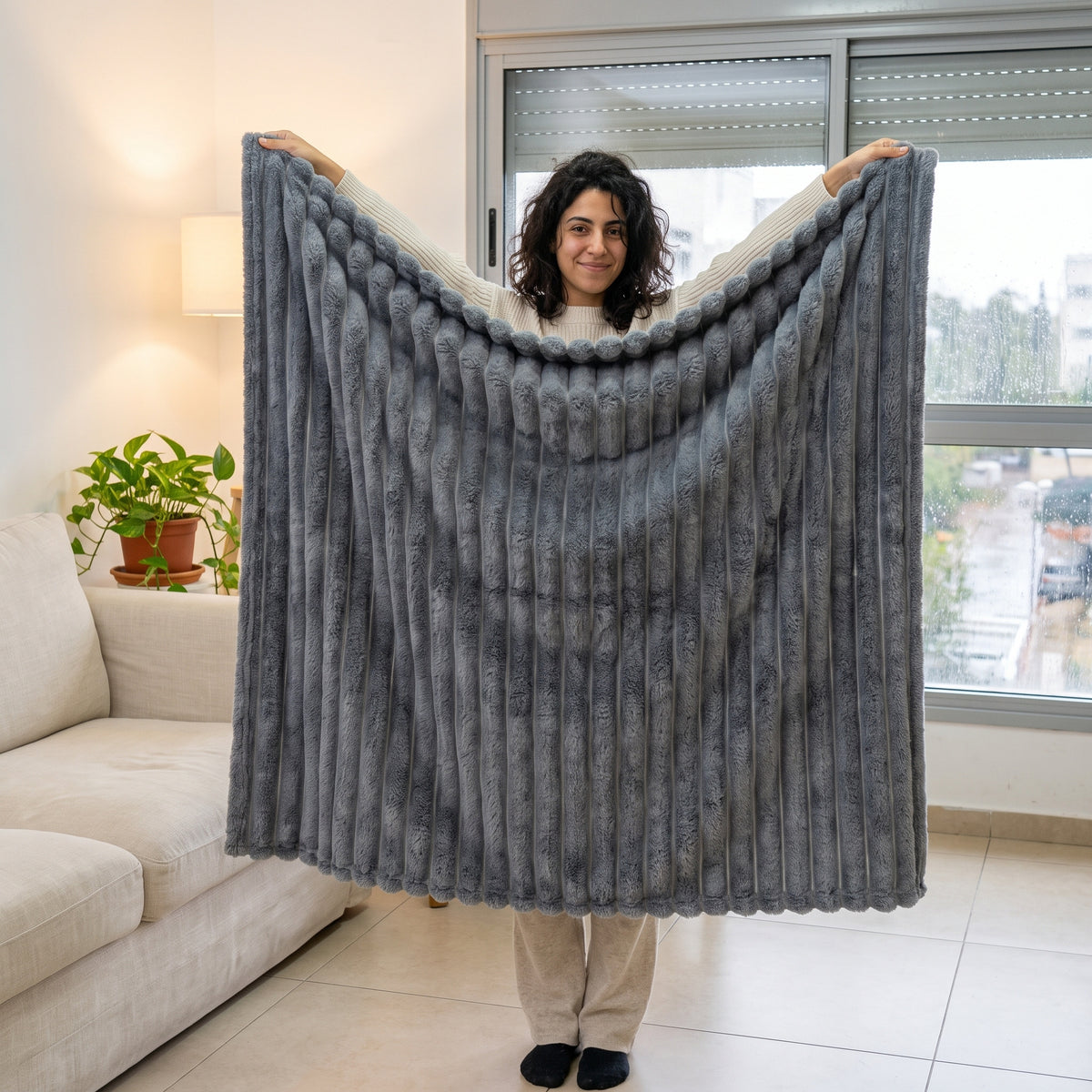 אישה מחזיקה שמיכת פלנל מפוספסת פרושה לכל גובהה בסלון